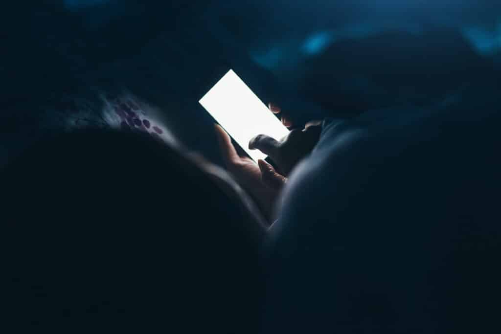 Woman texting and reading on smartphone in bed
