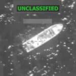 Grayscale surveillance image showing a long boat-shaped object on water with crosshair targeting marks and an ON-CLASSIFIED banner at the top.