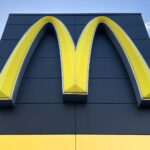 Large yellow McDonald's arches logo mounted on a dark blue building facade with a yellow base panel beneath