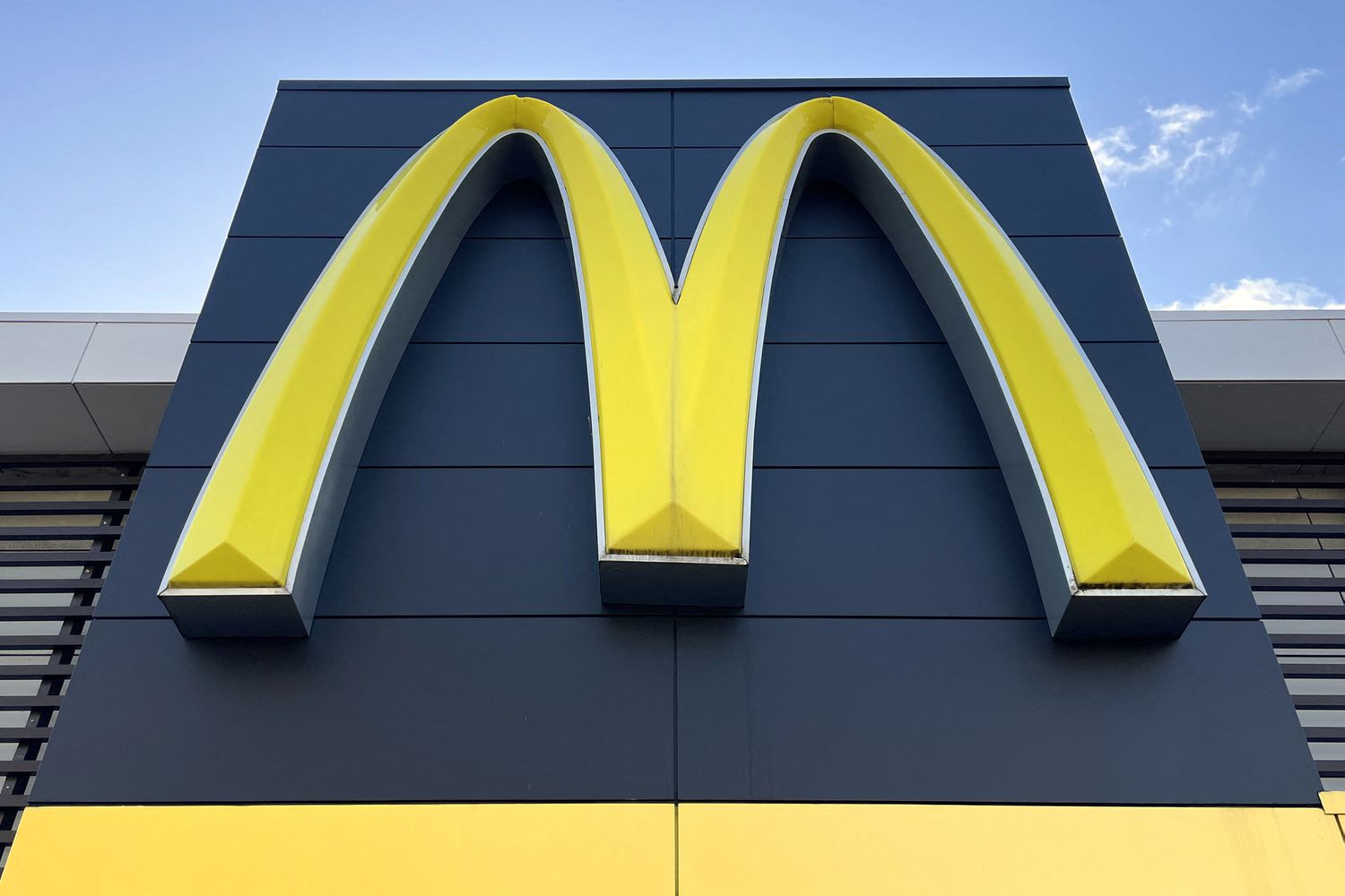 Large yellow McDonald's arches logo mounted on a dark blue building facade with a yellow base panel beneath