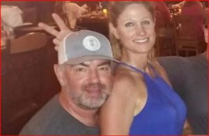 Smiling man wearing a gray baseball cap and a woman in a blue sleeveless dress posing together at a social event.