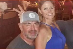 Smiling man wearing a gray baseball cap and a woman in a blue sleeveless dress posing together at a social event.