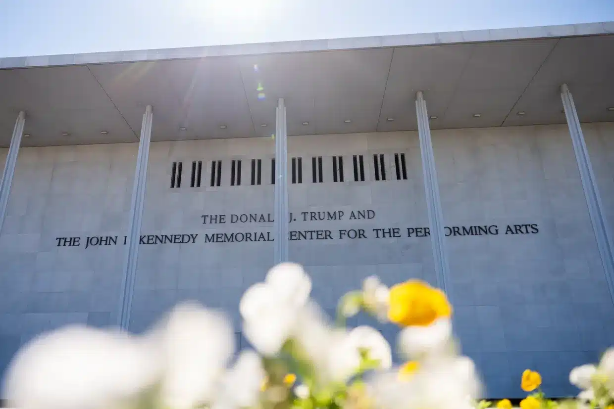 Front of the Donald J. Trump and John F. Kennedy Memorial Center for the Performing Arts, with blurred white and yellow flowers in the foreground.