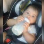 Baby seated in a car seat, drinking from a bottle.
