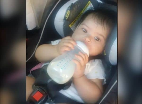 Baby seated in a car seat, drinking from a bottle.