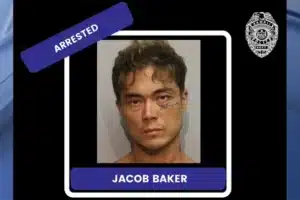 Mugshot of a man with short dark hair, a blue 'ARRESTED' banner, and a name plate reading 'JACOB BAKER' at the bottom.