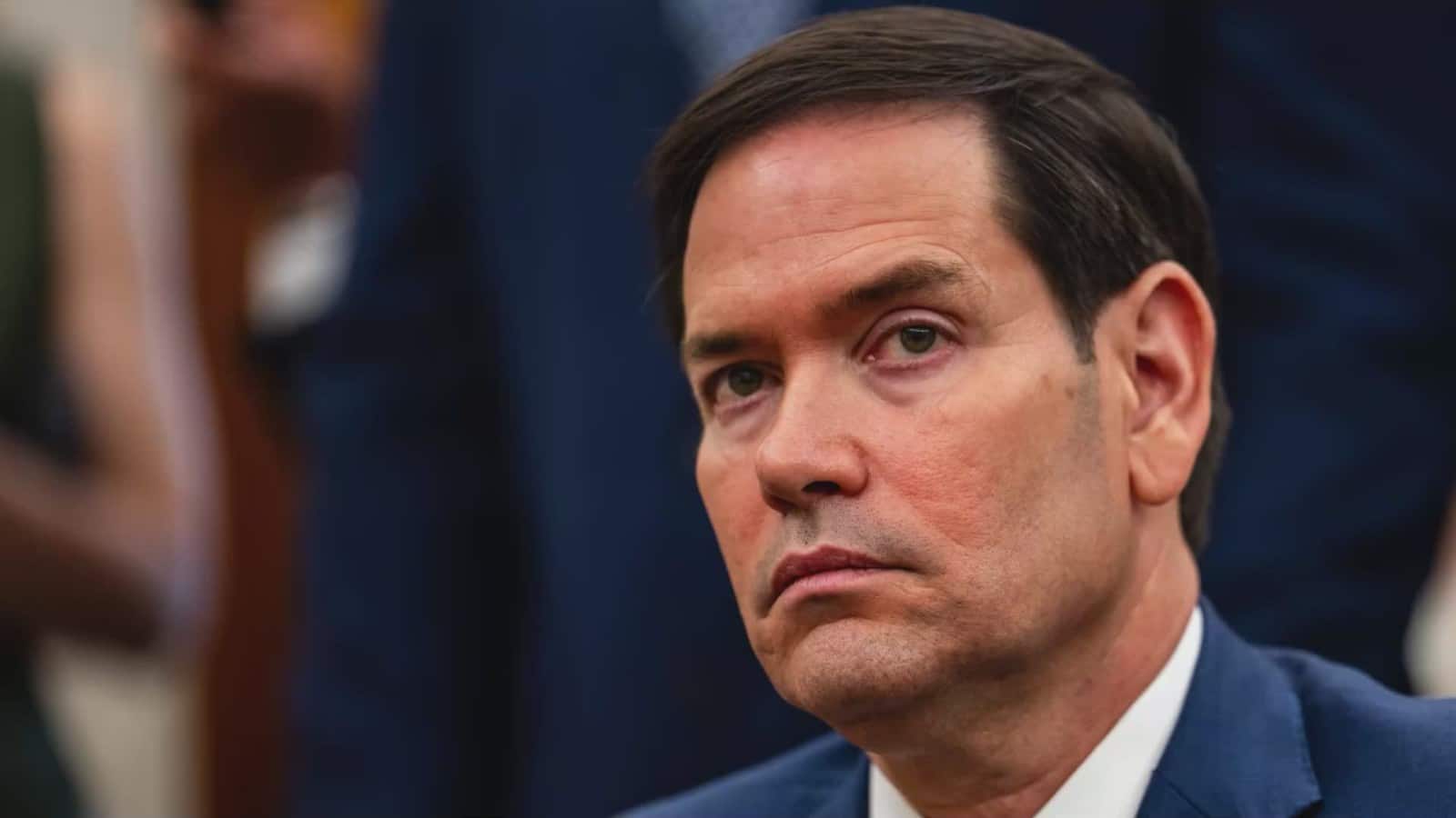 Close-up of a man in a blue suit with a serious expression.