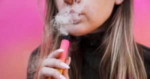 A,Young,Girl,Smokes,Disposable,Electronic,Cigarette.,Bright,Yellow,Background