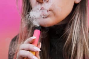 A,Young,Girl,Smokes,Disposable,Electronic,Cigarette.,Bright,Yellow,Background