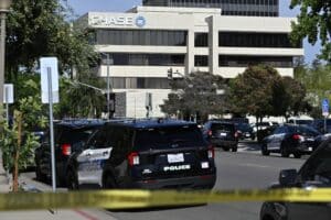 Police cars line a street in front of a Chase building, with yellow caution tape across the foreground indicating a restricted area.