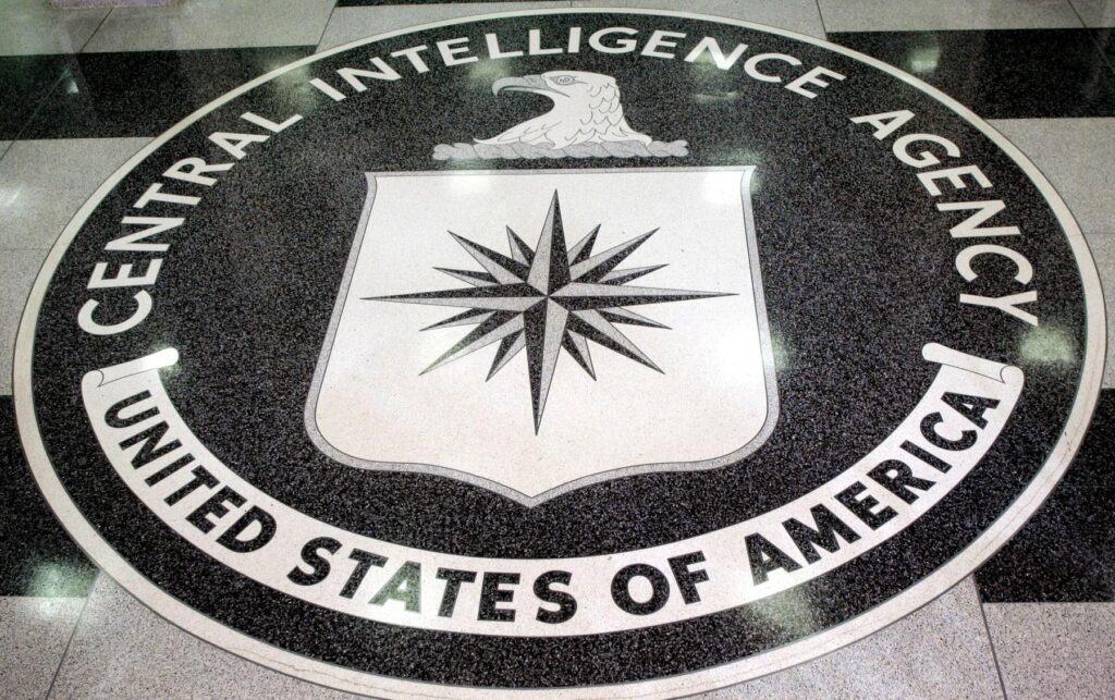 Circular CIA seal on the floor with the words 'Central Intelligence Agency' surrounding a white shield bearing a black compass rose and an eagle above it