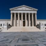 Exterior of the U.S. Supreme Court building with tall columns and wide stairs under a deep blue sky