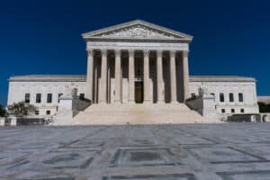 Exterior of the U.S. Supreme Court building with tall columns and wide stairs under a deep blue sky