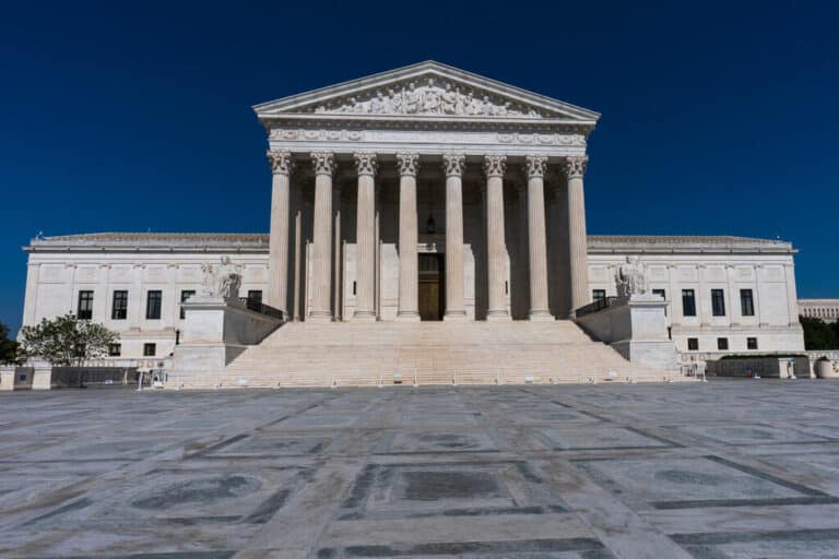 Exterior of the U.S. Supreme Court building with tall columns and wide stairs under a deep blue sky