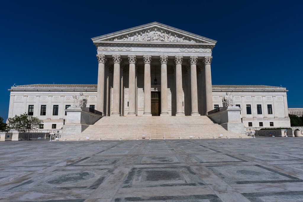 Exterior of the U.S. Supreme Court building with tall columns and wide stairs under a deep blue sky
