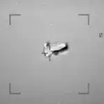 Night-vision style shot of a small aircraft centered in a square targeting reticle with corner brackets visible.