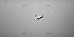 Night-vision style shot of a small aircraft centered in a square targeting reticle with corner brackets visible.