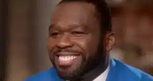 Close-up of a smiling man with a full beard, wearing a bright blue suit jacket.