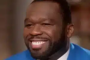 Close-up of a smiling man with a full beard, wearing a bright blue suit jacket.