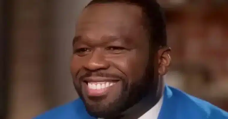 Close-up of a smiling man with a full beard, wearing a bright blue suit jacket.