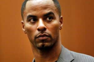 Man in a grey pinstripe suit, looking to his left with a focused expression.