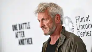 Portrait of a gray-bearded man in a dark shirt and olive jacket, standing at a Film at Lincoln Center event with the logo in the background.