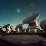 Row of large radio telescopes pointed toward a star-filled night sky.