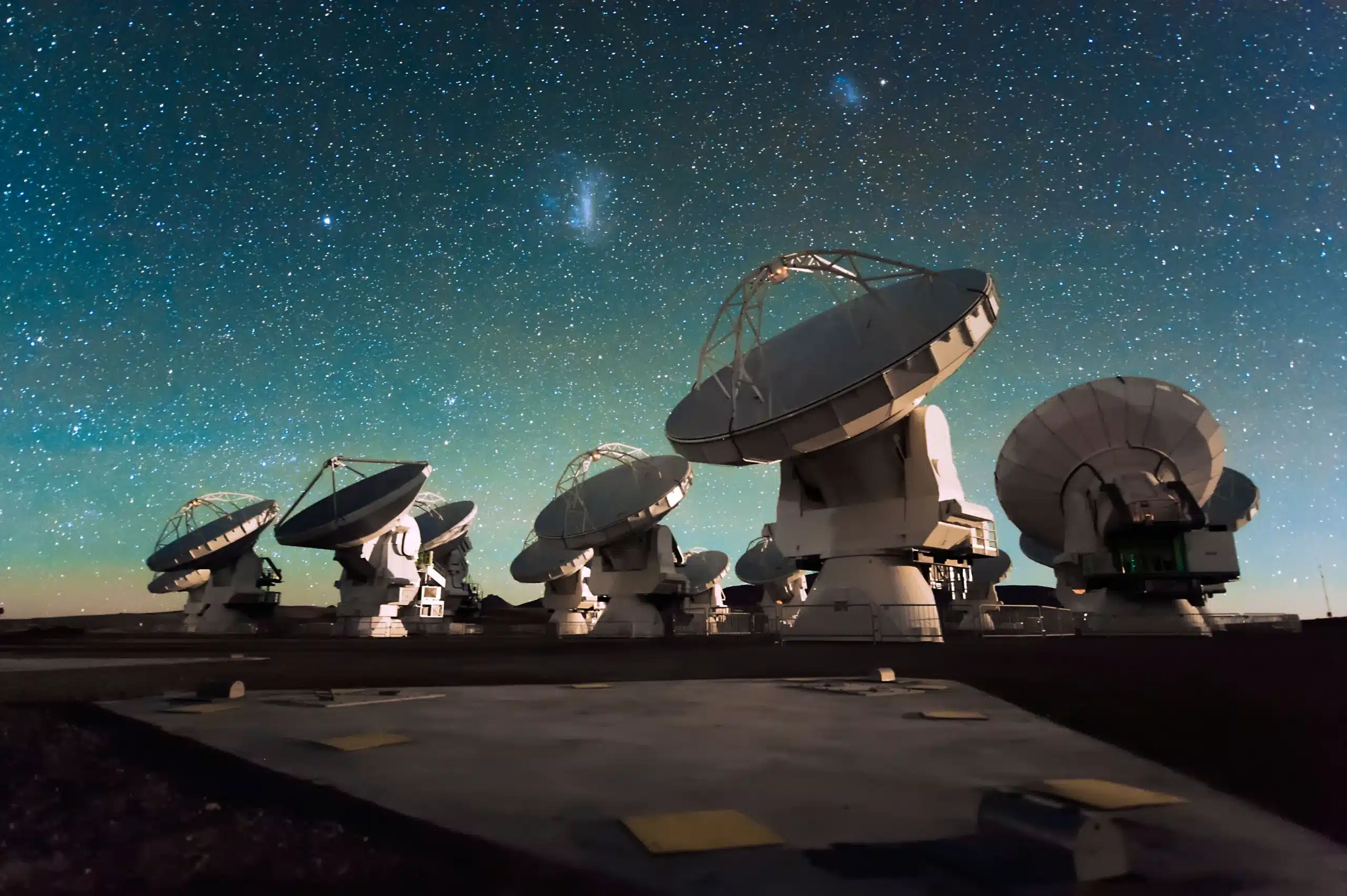 Row of large radio telescopes pointed toward a star-filled night sky.
