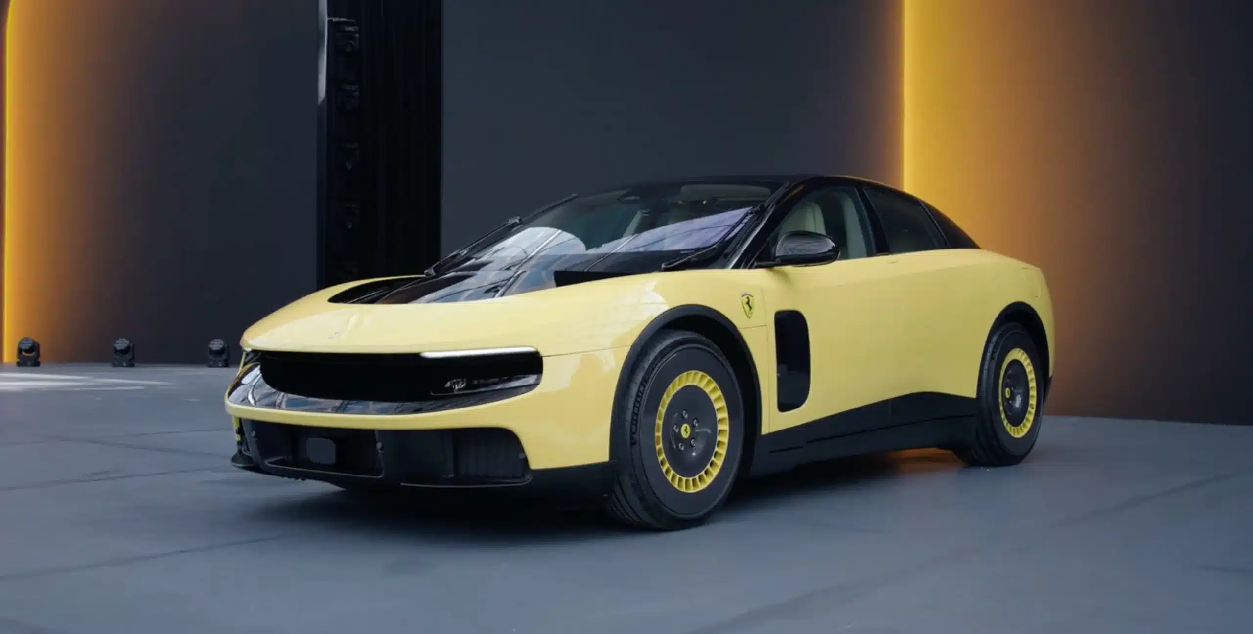 Front three-quarter view of a yellow Ferrari in a dark studio with orange vertical lights on either side.