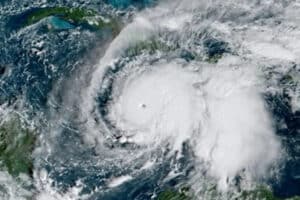 Satellite image of a large hurricane with a clear eye, spiraling white clouds over the Atlantic Ocean seen from space, near landmasses