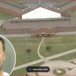 Aerial view of a fenced prison complex with a central building and surrounding grounds; a circular inset shows a man's mugshot in the lower-left corner.