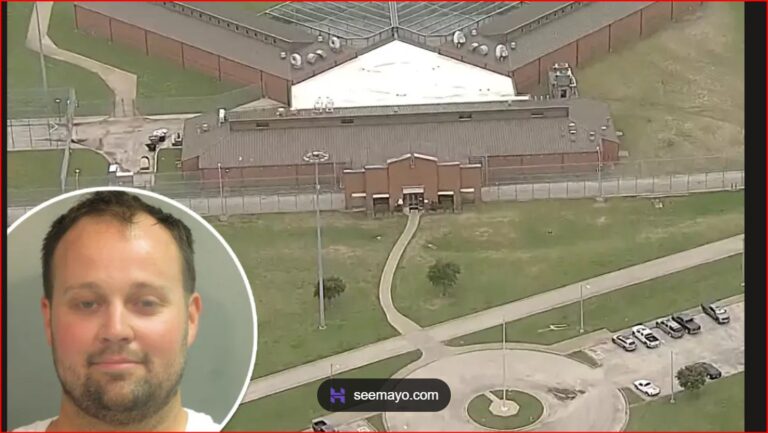 Aerial view of a fenced prison complex with a central building and surrounding grounds; a circular inset shows a man's mugshot in the lower-left corner.