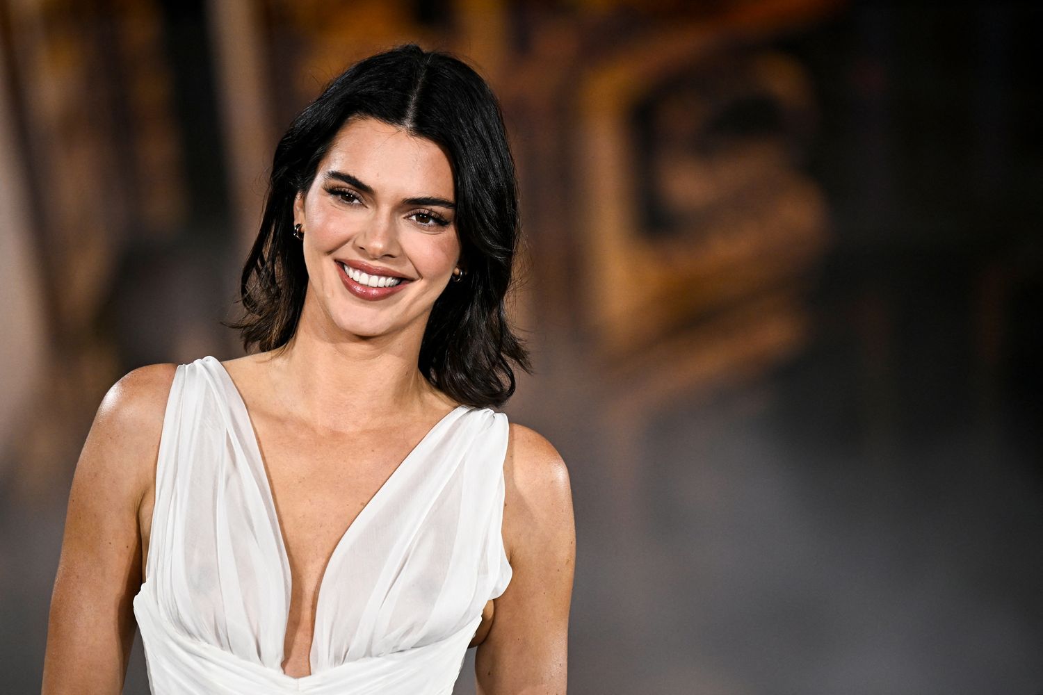 Smiling woman in a white plunging evening gown at a formal event on a red carpet image area