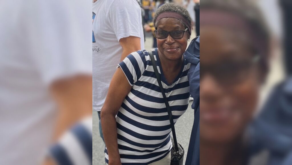 Smiling woman wearing a navy and white striped shirt, glasses, and a headband at an outdoor event.