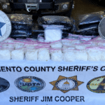 Display table of seized white powder in clear bags, with Sacramento County Sheriff's Office banner and sheriff badges in the background.