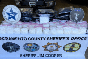 Display table of seized white powder in clear bags, with Sacramento County Sheriff's Office banner and sheriff badges in the background.