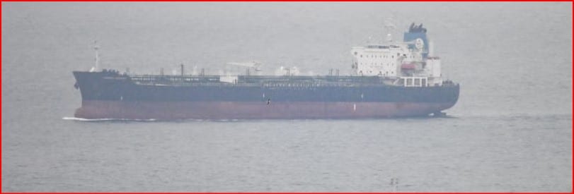 Large cargo ship on calm sea viewed from side, with a dark hull and white superstructure toward the sternsideside of the vessel.