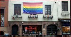 Rainbow Pride flag hangs above The Stonewall Inn on a brick building on a city street