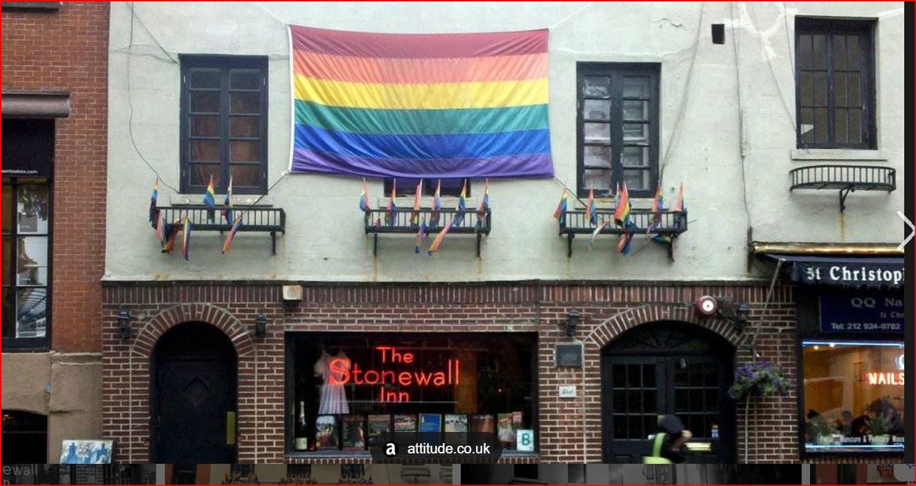 Rainbow Pride flag hangs above The Stonewall Inn on a brick building on a city street
