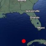Map showing a red earthquake dot in the Caribbean south of Cuba with a '6.1 MAGNITUDE' label in the top-left corner.