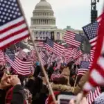 Crowd of people waving American flags in front of the U.S. Capitol dome in Washington, DC.