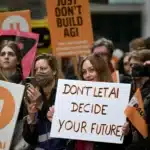 Protesters hold signs urging to pause AI, with a prominent white sign reading Don't Let AI Decide Your Future.