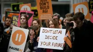 Protesters hold signs urging to pause AI, with a prominent white sign reading Don't Let AI Decide Your Future.
