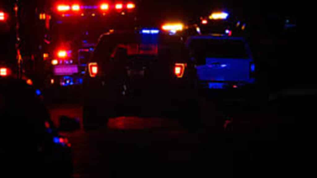 Nighttime scene of emergency vehicles with red and blue flashing lights in a row