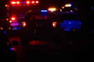 Nighttime scene of emergency vehicles with red and blue flashing lights in a row