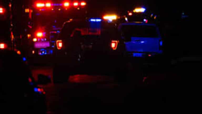 Nighttime scene of emergency vehicles with red and blue flashing lights in a row