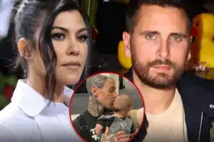 Man with extensive tattoos holding a baby, while a woman stands nearby, in a close-up group photo.