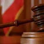 Judge's wooden gavel striking the sound block in a courtroom setting.