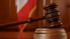 Judge's wooden gavel striking the sound block in a courtroom setting.
