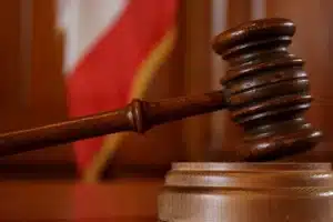 Judge's wooden gavel striking the sound block in a courtroom setting.